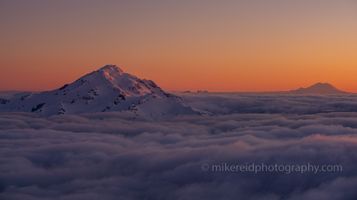 Over the North Cascades Glacier Peak and Mount Rainier Sunset Bathed in the first light of dawn, Glacier Peak rises majestically above a sea of clouds, its snow-clad slopes glowing in soft pink and amber hues. In the...