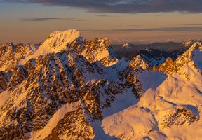 Over the North Cascades Mount Baker and South Sister Bathed in the first light of sunrise, the jagged spires and snow-covered ridges of the North Cascades blaze with rich alpenglow hues. Captured from the air with...