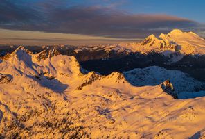 Over the North Cascades Mount Baker and Twin Sisters Bathed in warm alpenglow, the rugged peaks of the Sisters Range unfold beneath Mount Baker’s towering, snow-draped summit in this breathtaking aerial...