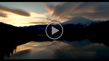 Mount Baker Sunset Cloudscape Video Stunning 4K aerial footage of Mount Baker glowing in golden light above the calm waters of Baker Lake. Clouds drift through the North Cascades as the setting...
