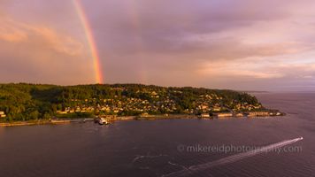 Over Mukilteo Sunset Rainbow Over the Ferry Aerial Photography.jpg A dramatic aerial view of a rainbow arching over the Mukilteo ferry dock and the Puget Sound shoreline. Evening light illuminates the coastal homes and forested...