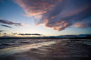 Discovery Park MAgnolia Beach Skies Vivid sunset clouds sweep across the sky above Discovery Park Beach, their fiery tones mirrored in the wet sand and rippling tide. The last light fades over...