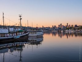 Seattle Lake Union Moorage Vintage boats moored on Lake Union at dawn with the Seattle skyline glowing in the soft morning light and golden reflections across calm water.