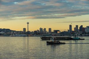 Elliott Bay Working Harbor Space Needle Tugboats and barges move across Elliott Bay with the Seattle skyline and Space Needle in the background under soft evening light.