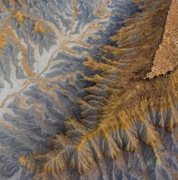 Erosion Patterns Below a Utah Mesa — Aerial Desert Landscape An aerial view of a Utah mesa reveals a mesmerizing landscape sculpted by wind and water. The ridges and canyons flow outward in organic patterns of gold, slate...