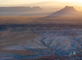 Sunset Over Factory Mesa, Utah — Aerial Desert Landscape An aerial view of Factory Mesa, Utah, bathed in the warm glow of sunset light. The scene unfolds in layers of golden desert, blue clay canyons, and rugged...