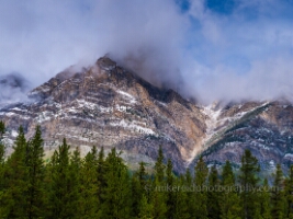 Misty Peaks Above Saskatchewan River Crossing – Canadian Rockies Drama | GFX100S Low clouds drift across rugged mountain peaks above the forests near Saskatchewan River Crossing in the Canadian Rockies. Captured with the Fujifilm GFX100S,...
