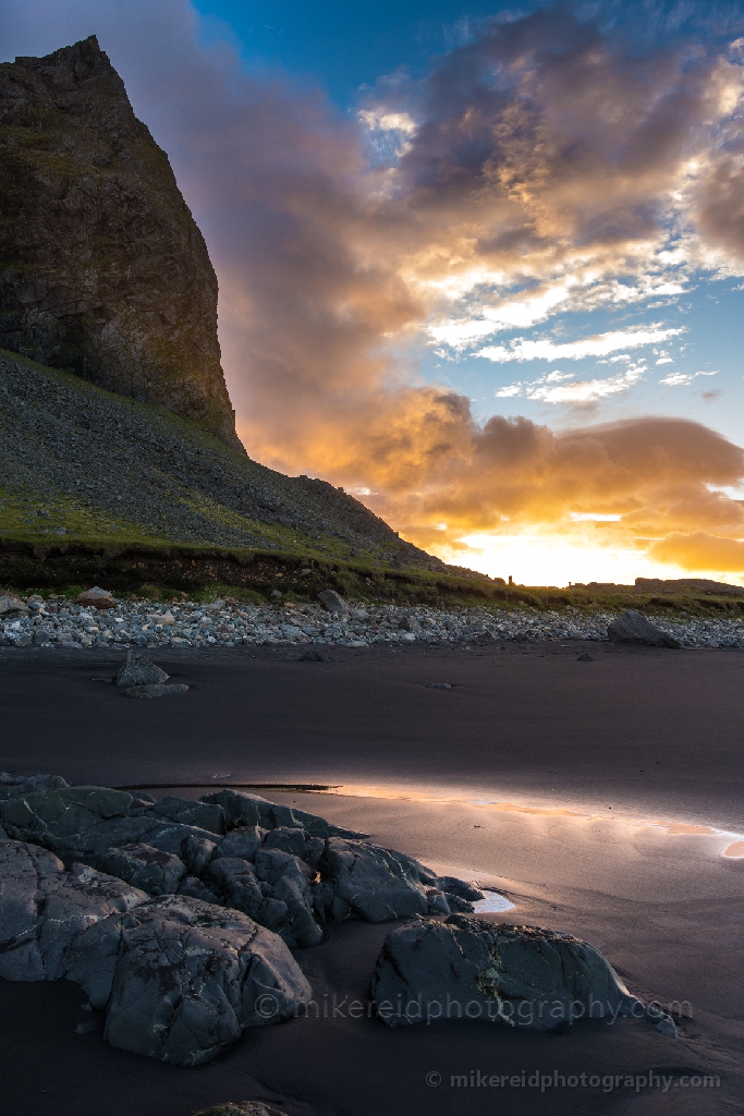Iceland Stokksnes Vestrahorn Rockscape A brilliant sunrise ignites the sky behind the jagged peaks of Vestrahorn, mirrored in the wet sands of Stokksnes Beach.