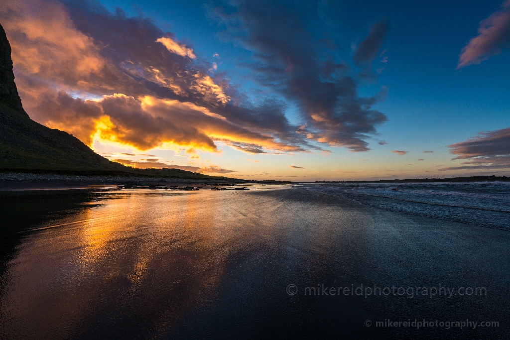 Sunrise Waves Retreating along Stokksnes Beach Iceland Golden sunrise light bursts through dramatic coastal clouds as waves retreat across the black sands of Stokksnes Beach in southeastern Iceland. The wet shoreline mirrors the morning sky, blending warmth and motion in a fleeting moment of natural beauty. Fine-art seascape photograph by Mike Reid capturing the rhythm and color of Iceland’s dawn.
