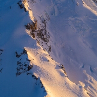 Over the North Cascades Mount Baker Details An intimate aerial view of Mount Baker’s west face reveals sweeping snowfields, jagged icefalls, and deeply carved glacial textures glowing under the golden...