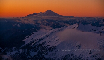 Over the North Cascades Mount Baker Sunset Light Aerial The last light of day paints Mount Baker and the surrounding North Cascades in glowing orange and violet tones as clouds drift among the peaks. Captured from...