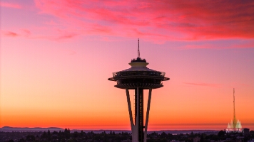 Aerial Seattle Sunset Space Needle Clouds The Seattle Space Needle glows under a vivid sunset sky above Queen Anne Hill. Brilliant shades of orange, pink, and purple fill the horizon, capturing the...