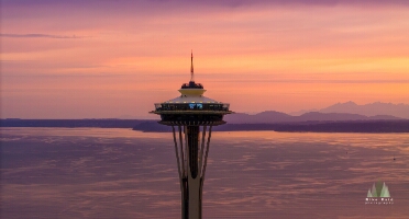 Aerial Seattle Sunset Space Needle Elliott Bay An aerial sunset view of Seattle’s Space Needle overlooking Puget Sound and the distant Olympic Mountains. The sky glows in warm tones of orange, pink, and...