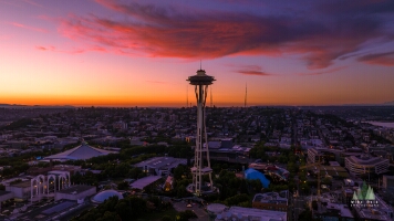 Aerial Seattle Sunset Space Needle Fiery Clouds A stunning aerial view of the Space Needle at sunset over Seattle’s Queen Anne Hill. The sky glows with vivid orange, pink, and purple tones as the city lights...