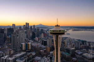 Over Seattle Space Needle Closeup and City at Sunrise Aerial sunrise view of the Seattle skyline with the Space Needle in the foreground and Mount Rainier glowing in the distance. Golden morning light illuminates...
