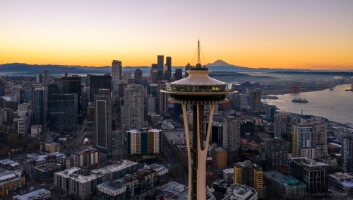 Over Seattle Space Needle Closeup at Sunrise Aerial sunrise view of the Seattle skyline with the Space Needle in the foreground and Mount Rainier glowing in the distance. Golden morning light illuminates...