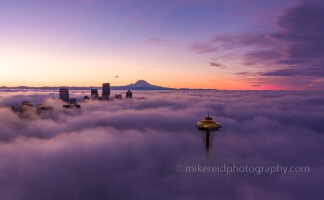 Over Seattle Space Needle on the Clouds A breathtaking aerial sunrise above the clouds over Seattle, with the Space Needle and downtown skyline emerging through the fog. Mount Rainier glows in the...