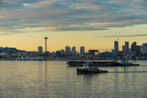 Elliott Bay Working Harbor Space Needle Tugboats and barges move across Elliott Bay with the Seattle skyline and Space Needle in the background under soft evening light.