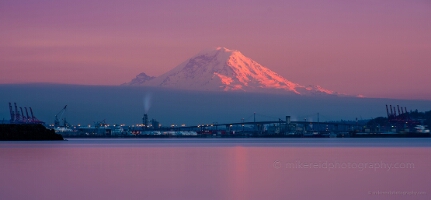 Mount Rainier Gentle Reflection 200mm Mount Rainier glowing in pink alpenglow above Tacoma’s waterfront and industrial port at sunrise, with the city bridge and calm waters of Puget Sound in the...