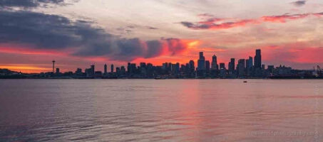 Seattle Fiery Sunrise From Alki West Seattle Fiery sunrise over the Seattle skyline viewed from West Seattle, with the Space Needle silhouetted against vivid red and purple clouds reflecting across Elliott...