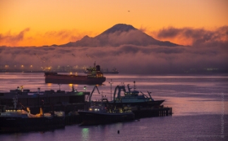 Seattle Photography Rainier and Pier 90 at Dawn Mount Rainier rising above low morning fog and glowing orange sunrise skies, viewed from Pier 90 in Seattle with cargo ships and fishing vessels anchored in...
