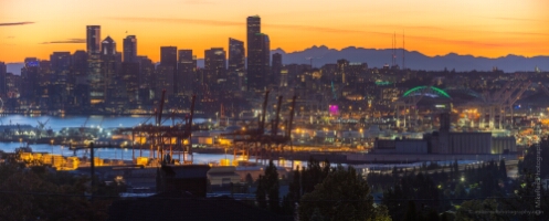Seattle Skyline and Port from West Seattle at Sunset From atop West Seattle, this breathtaking panoramic view captures the Seattle skyline glowing against a brilliant orange and gold sunset. The cranes and lights...