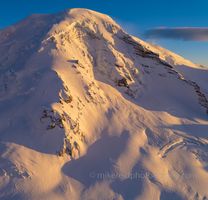 Over the North Cascades Mount Baker Details and Glaciers An intimate aerial view of Mount Baker’s west face reveals sweeping snowfields, jagged icefalls, and deeply carved glacial textures glowing under the golden...