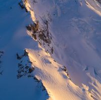Over the North Cascades Mount Baker Details An intimate aerial view of Mount Baker’s west face reveals sweeping snowfields, jagged icefalls, and deeply carved glacial textures glowing under the golden...