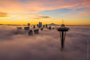 Over Seattle Space Needle Above the Fog A breathtaking sunrise over Seattle as the Space Needle rises above a sea of fog, with the downtown skyline and Mount Rainier glowing softly in the morning...