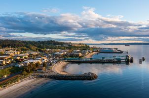 Aerial View of Edmonds Ferry Dock and Waterfront at Sunset An aerial view of the Edmonds Ferry Dock captures the golden evening light illuminating the waterfront, beach, and coastal town along Puget Sound. The gentle...