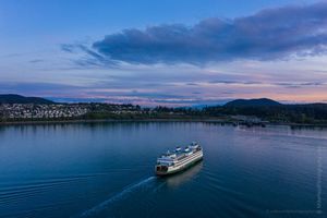 Over San Juan Islands Anacortes Ferry Arriving at Sunset Aerial Photography A Washington State ferry glides into Anacortes at dusk beneath a soft pastel sky. The fading twilight casts gentle tones of blue and lavender across the calm...