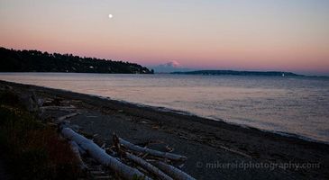 Discovery Park Evening Soft twilight colors wash over Puget Sound as Mount Rainier glows in the distance and the moon rises above the quiet shoreline at Discovery Park. Driftwood...