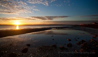 Fiery Discovery Park Sunset Tidepool The first light of day spreads across Puget Sound, casting golden hues over the calm waters and sandy shoreline of Discovery Park. Reflections shimmer in the...
