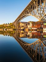 Seattle Lake Union Houseboats and Aurora Bridge Vertical Reflection Vertical view of Seattle’s Aurora Bridge and colorful Lake Union houseboats reflected symmetrically in calm morning water under golden sunlight.