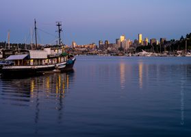 Seattle Skyline and Tug at Sunset Fishing boat and houseboats on Lake Union at sunset with downtown Seattle’s skyline glowing in golden light and reflected in the calm water.