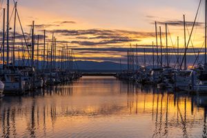 Seattle Photography Shilshole Marina Dusk Skies Golden sunset over Shilshole Bay Marina in Seattle, with rows of sailboats reflecting on calm water beneath glowing clouds and warm evening light.