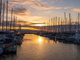 Seattle Photography Shilshole Marina Sunset Light Warm sunset over Shilshole Bay Marina in Seattle with rows of sailboats reflecting golden light on rippling water beneath a glowing Pacific Northwest sky.