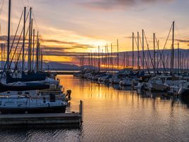 Seattle Photography Shilshole Marina Sunset Moorage Golden sunset over Shilshole Bay Marina in Seattle with symmetrical rows of sailboats glowing in evening light reflected on the calm water.