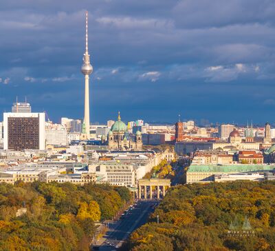 Brandenburg Gate and Berlin Skyline in Autumn A panoramic aerial view across Berlin in autumn, looking over the golden canopy of the Tiergarten toward the Brandenburg Gate and the historic city center. The...