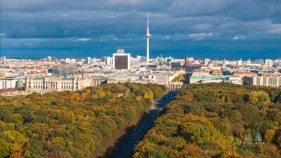 Tiergarten to Brandenburg Gate and Berlin Skyline A sweeping aerial view across Berlin’s Tiergarten in autumn, looking along the central avenue toward the Brandenburg Gate and the historic city center. The...