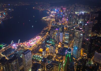 Hong Kong Central Waterfront and Victoria Harbour at Night Aerial A dramatic nighttime drone view over Hong Kong's Central waterfront reveals illuminated skyscrapers, glowing streets, and the dark waters of Victoria Harbour....