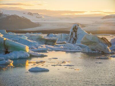 Sunset Glow on Jökulsárlón Glacier Lagoon – Iceland Ice Reflections Golden sunset light illuminates floating icebergs in Iceland’s Jökulsárlón Glacier Lagoon, with Vatnajökull’s snowy expanse rising beyond. Captured by Mike Reid...