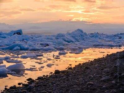 Sunset Glow over Jökulsárlón Ice and Shoreline – Iceland Glacier Lagoon Soft golden and rose tones reflect off melting ice along the shoreline of Jökulsárlón Glacier Lagoon in Iceland. Captured by Mike Reid Photography, this...