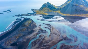 Over Iceland Braided Beach River Tidal Abstract An ethereal aerial photograph over the Stokksnes estuary in southeastern Iceland, where glacial meltwater fans into the sea beneath the dramatic peaks of...