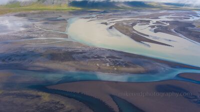 Iceland Braided River Estuary Aerial – Glacial Meltwater Patterns A striking aerial view of Iceland’s braided river estuary, where glacial meltwater fans into a tapestry of turquoise, ivory, and volcanic black. Captured by...