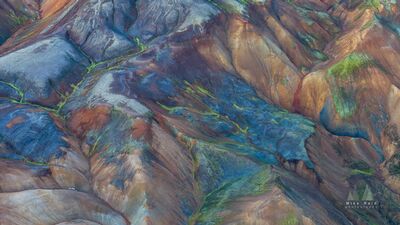Blue and Gold Rhyolite Ridges of Landmannalaugar An aerial view of the richly colored rhyolite mountains of Landmannalaugar in Iceland’s Highlands. Blue-gray mineral slopes, warm gold and rust ridges, and...