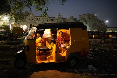Preparing for the Chennai Flower Market at 5 AM Two women prepare flowers beside a yellow auto rickshaw in the predawn darkness of Chennai, India. Photographed around 5 a.m. as the flower market begins to...