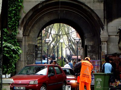 Historic Stone Archway and Street Life in Istanbul Turkey Everyday street life unfolds beneath a monumental stone archway near Istanbul's historic Grand Bazaar in Turkey. A municipal sanitation worker in a bright...