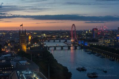 London Eye and the Thames at Sunset A sweeping evening view over central London, England, with the London Eye glowing beside the River Thames as the last light of sunset fades across the horizon....