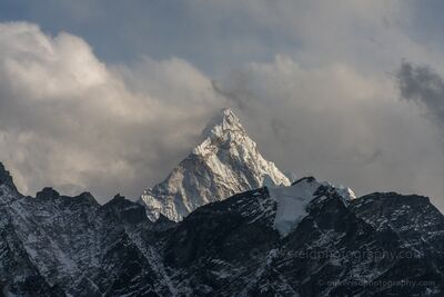 Ama Dablam Emerging Through Himalayan Clouds from Kala Patthar The distinctive pyramidal summit of Ama Dablam rises above dark, snow-dusted mountain ridges in Nepal's Khumbu region, photographed from Kala Patthar. Soft...